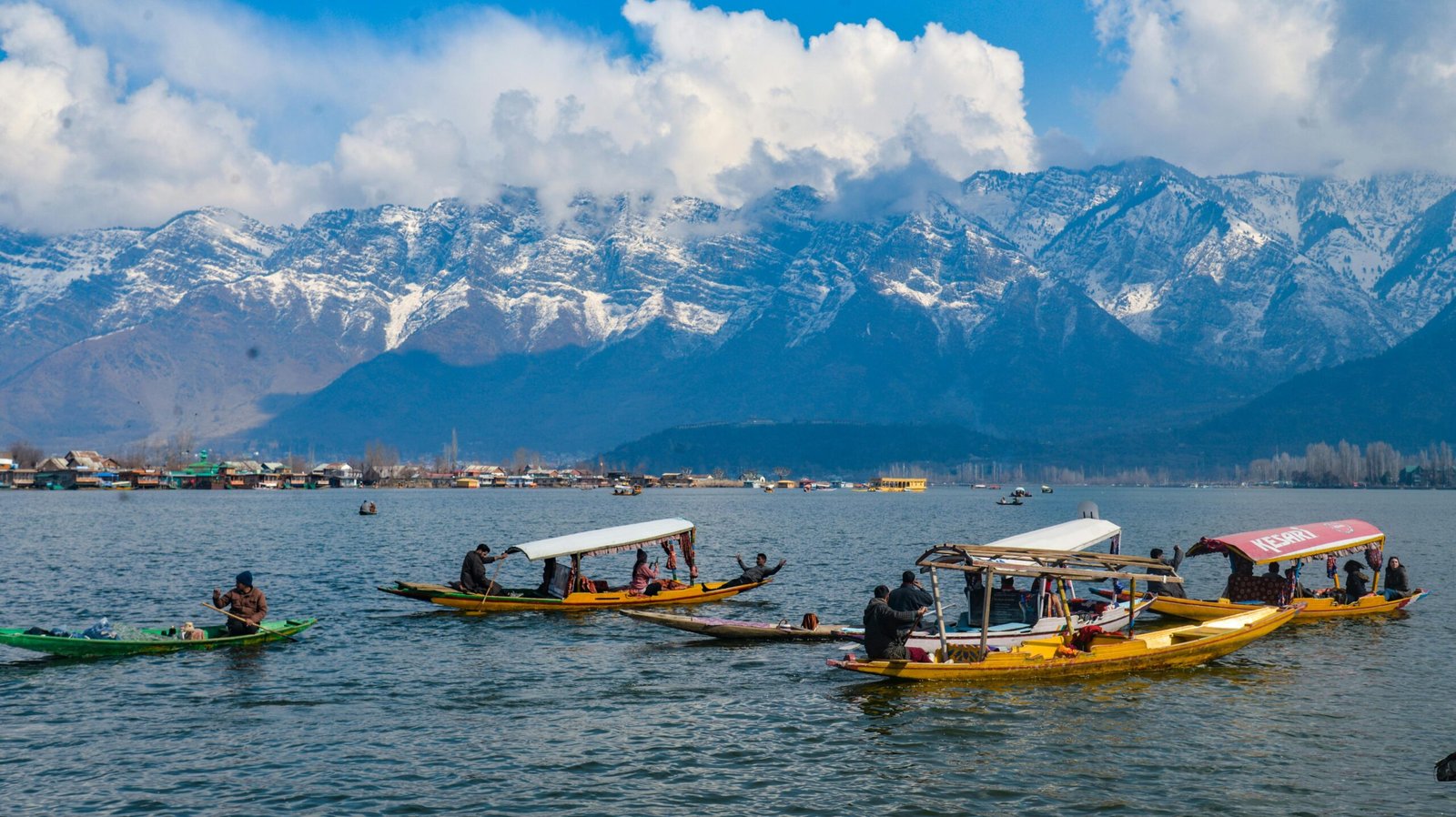 Boats on Dal Lake with majestic snow-capped Himalayas in the background.