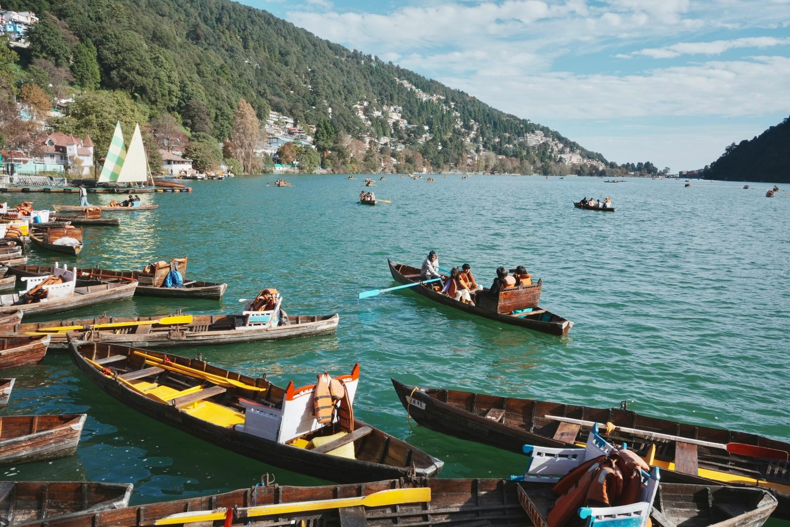 Wooden boats on Nainital Lake against lush hills, perfect for a serene getaway.