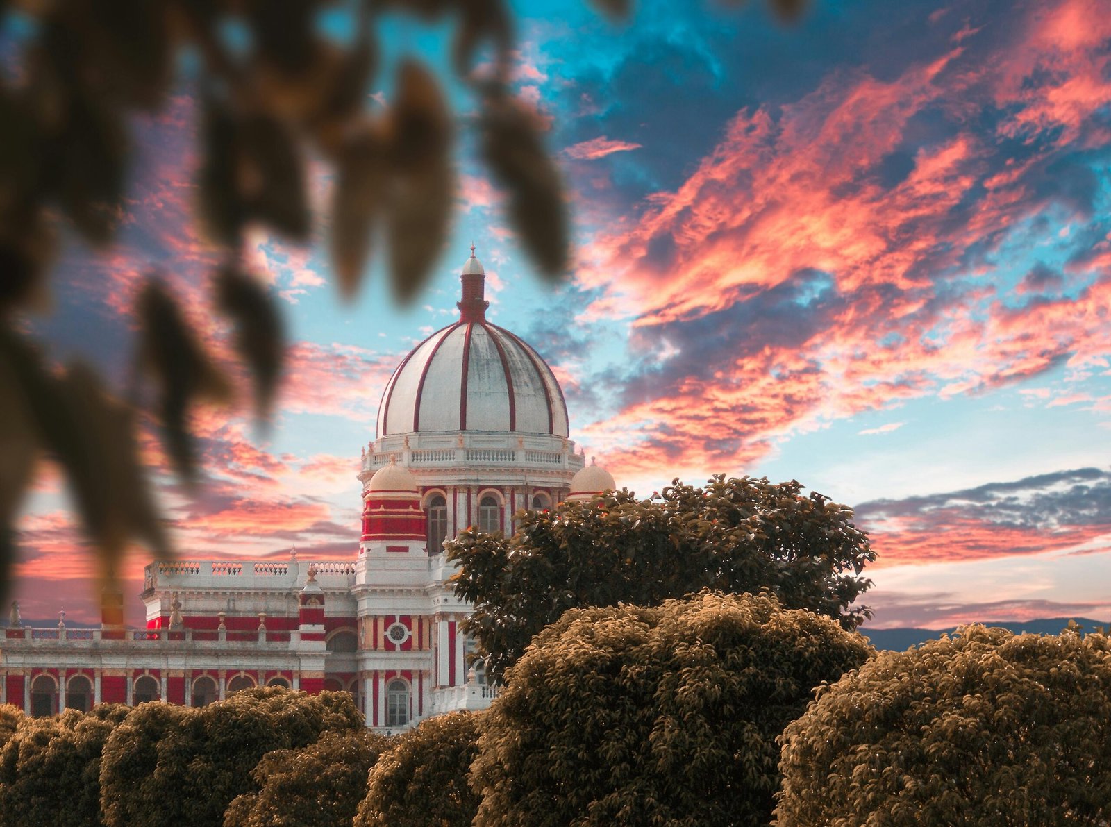 Elegant dome architecture captured against a breathtaking sunset sky, flanked by lush greenery.