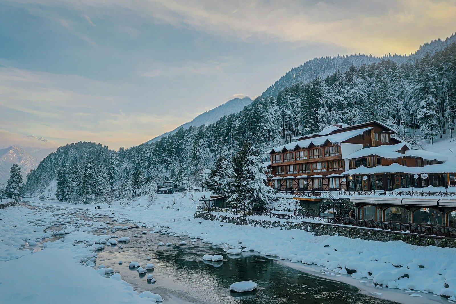 A beautiful winter scene of Pahalgam, Kashmir with snow-covered landscapes and serene river view.