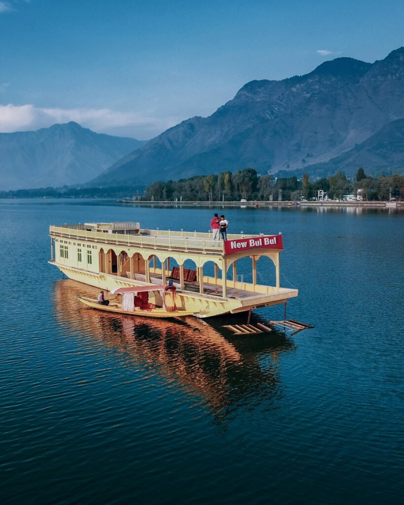 A vibrant houseboat on Dal Lake with stunning mountain backdrop, perfect for travel and leisure.