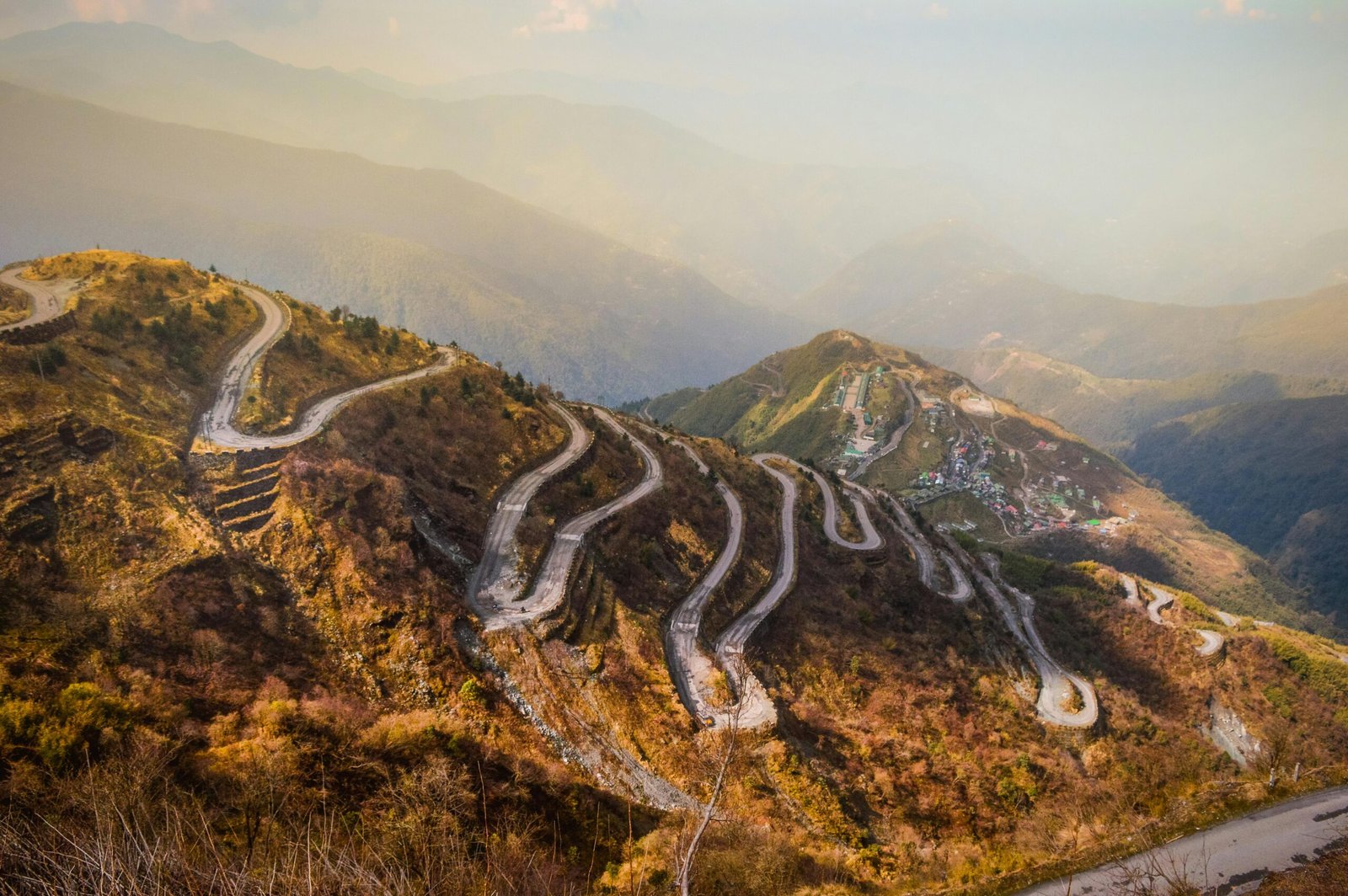 Aerial view of a winding road through the mountains of Sikkim, India, during a sunny day.